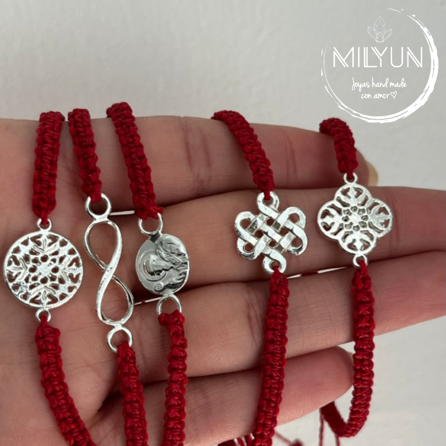 Pulsera roja tejida con macramé y símbolos de plata.